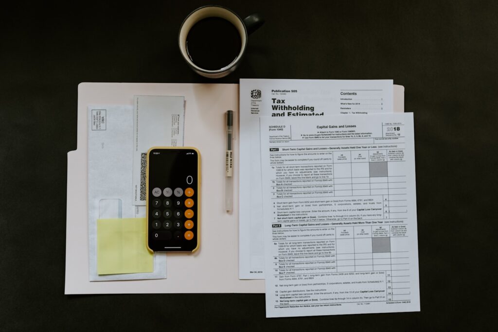 black Android smartphone near ballpoint pen, tax withholding certificate on top of white folder